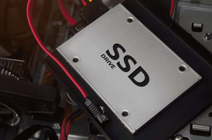 SSD drive laying on computer case with cables and mounts.