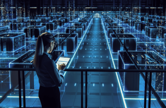 Female IT specialist using tablet computer overlooking a data center.